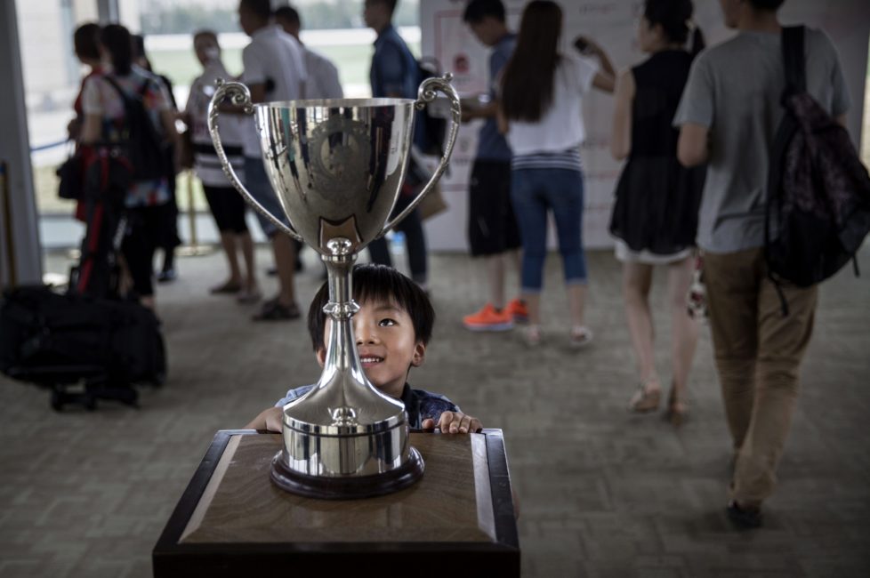 TIANJIN, CHINA - JULY 17: A Chinese boy looks at the cup before tournament play at the Tianjin Goldin Metropolitan Polo Club on July 17, 2016 in Tianjin, China. China's rising affluence has nurtured growing interest in polo and other past-times regarded as noble or prestigious by the country's elite. Clubs and international-size polo fields have been built in various cities including Beijing and Shanghai, and on the outskirts of Tianjin, where membership at the exclusive Goldin Metropolitan, China's largest polo club, is by invitation-only and fees can be significant for polo team owners. Increasingly, wealthy Chinese parents are choosing polo and other equestrian activities for their children as a way to bolster their credentials for admission to top-tier universities in the United States and the United Kingdom. While the so-called "sport of kings" became a mainstay in Hong Kong during the era of British rule, polo is a relatively new sport to mainland China. Professional polo players are frequently flown in from countries such as New Zealand and Argentina in order to field competitive matches. Many of the polo clubs in China are tied to luxury real estate developments. (Photo by Kevin Frayer/Getty Images)