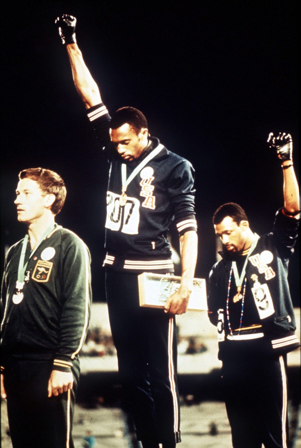 1968 Olympic Games, Mexico City, Mexico, Men's 200 Metres Final, USA gold medallist Tommie Smith (C) and bronze medallist John Carlos give the black power salutes as an anti-racial protest as they stand on the podium with Australian silver medallist Peter Norman (Photo by Rolls Press/Popperfoto/Getty Images)