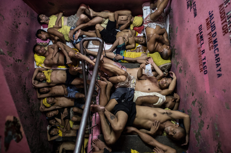 In this photo taken on July 21, 2016 inmates sleep on the steps of a ladder inside the Quezon City jail at night in Manila. There are 3,800 inmates at the jail, which was built six decades ago to house 800, and they engage in a relentless contest for space. Men take turns to sleep on the cracked cement floor of an open-air basketball court, the steps of staircases, underneath beds and hammocks made out of old blankets. / AFP PHOTO / NOEL CELIS / TO GO WITH AFP STORY: Philippines-politics-crime-jails, FOCUS by Ayee Macaraig