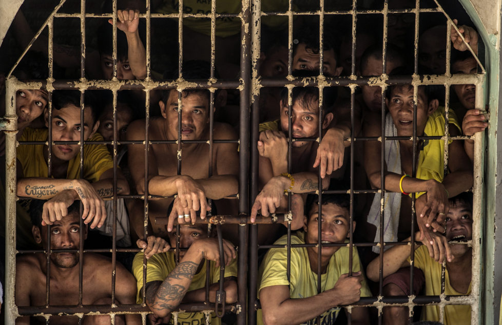 Inmates peek from their cell inside the Quezon City Jail in Manila in this picture taken on July 18, 2016. There are 3,800 inmates at the jail, which was built six decades ago to house 800, and they engage in a relentless contest for space. Men take turns to sleep on the cracked cement floor of an open-air basketball court, the steps of staircases, underneath beds and hammocks made out of old blankets. / AFP PHOTO / NOEL CELIS / TO GO WITH AFP STORY: Philippines-politics-crime-jails, FOCUS by Ayee Macaraig