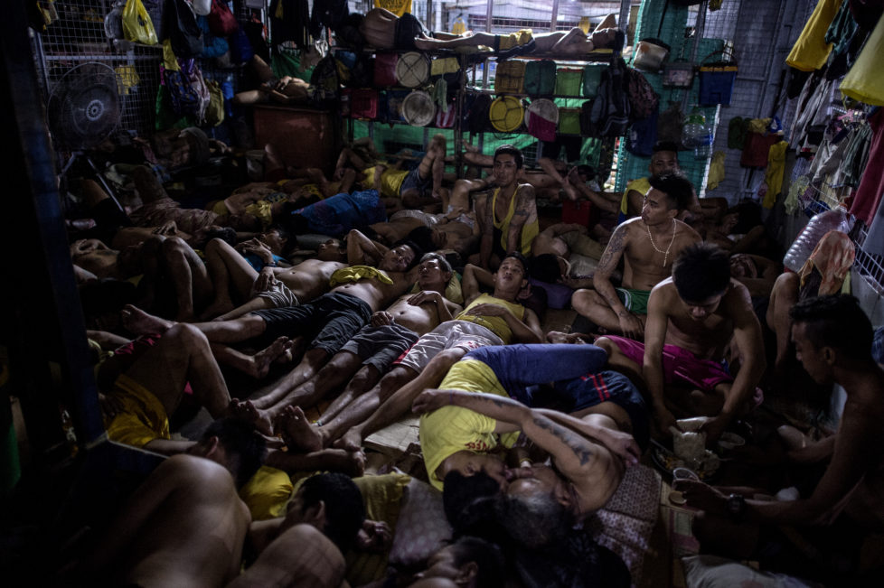Inmates rest in their sleeping quarters inside the Quezon City jail at night in Manila in this picture taken on July 18, 2016. There are 3,800 inmates at the jail, which was built six decades ago to house 800, and they engage in a relentless contest for space. Men take turns to sleep on the cracked cement floor of an open-air basketball court, the steps of staircases, underneath beds and hammocks made out of old blankets. / AFP PHOTO / NOEL CELIS / TO GO WITH AFP STORY: Philippines-politics-crime-jails, FOCUS by Ayee Macaraig