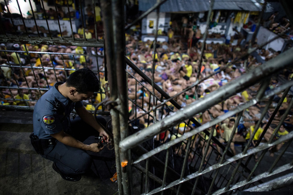 A prison guard locks a gate inside the Quezon City jail at night in Manila in this picture taken on July 21, 2016. There are 3,800 inmates at the jail, which was built six decades ago to house 800, and they engage in a relentless contest for space. Men take turns to sleep on the cracked cement floor of an open-air basketball court, the steps of staircases, underneath beds and hammocks made out of old blankets. / AFP / NOEL CELIS / TO GO WITH AFP STORY: Philippines-politics-crime-jails, FOCUS by Ayee Macaraig (Photo credit should read NOEL CELIS/AFP/Getty Images)