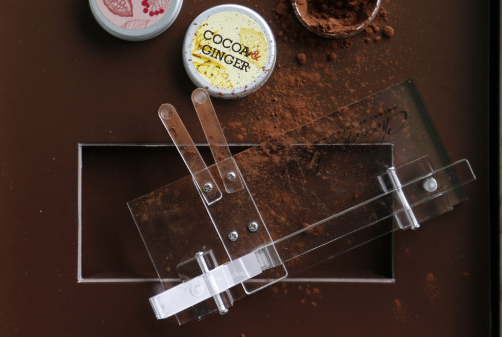 A Chocolate Shooter is displayed near cocoa powder in the factory of Belgian chocolatier Dominique Persoone in Bruges, February 3, 2015. When Belgian chocolatier Dominique Persoone created a chocolate-sniffing device for a Rolling Stones party in 2007, he never imagined demand would stretch much beyond the rock 'n' roll scene. But, seven years later, he has sold 25,000 of them. Inspired by a device his grandfather used to propel tobacco snuff up his nose, Persoone created a 'Chocolate Shooter' to deliver a hit of Dominican Republic or Peruvian cocoa powder, mixed with mint and either ginger or raspberry. Picture taken on February 3, 2015. REUTERS/Francois Lenoir (BELGIUM - Tags: FOOD SOCIETY) - RTR4OIJX