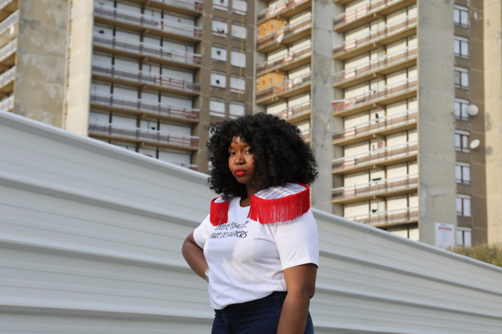 Designer Aisse N'diaye poses for a picture wearing a shirt from her brand Afrikanista in Clichy-sous-Bois, France, August 26, 2016. N'diaye grew up in Clichy-sous-bois, where her parents currently reside. Behind her is the La Forestiere housing where she grew up, and which is now slated for demolition. REUTERS/Joe Penney SEARCH "CREATIVE BANLIEUE" FOR THIS STORY. SEARCH "WIDER IMAGE" FOR ALL STORIES. THE IMAGES SHOULD ONLY BE USED TOGETHER WITH THE STORY - NO STAND-ALONE USES.