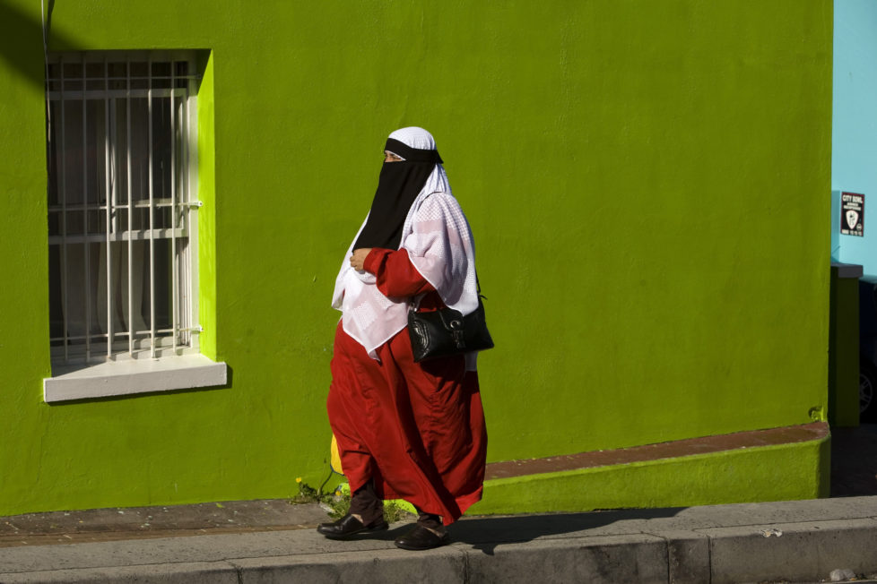CAPE TOWN, SOUTH AFRICA - SEPTEMBER 30 - A Muslim woman walks past a brightly-painted building in this Cape Malay neighborhood called Bo Kaap. (Photo by Melanie Stetson Freeman/The Christian Science Monitor/Getty Images)