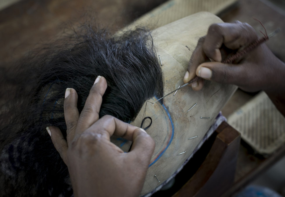 CHENNAI, INDIA - NOVEMBER 11: A worker hand makes a wig at Raj Hair International November 11, 2016 in Thiruttani, India. Raj Hair International donates wigs to cancer patients in India and also exports hair products, including weaves and wigs, to 56 countries. All of the hair they export comes from Tamil Nadu, 1/4 of which is temple hair and the rest comes from comb waste that people sell. They estimate that it takes 1 full month to make one wig by hand. The process of shaving ones hair and donating it to the Gods is known as tonsuring. It is common for Hindu believers to tonsure their hair at a temple as a young child, and also to celebrate a wish coming true, such as the birth of a baby or the curing of an illness. The "temple hair", as it's known, is then auctioned off to a processing plant and then sold as pricey wigs and weaves in the US, Europe and Africa. (Photo by Allison Joyce/Getty Images)