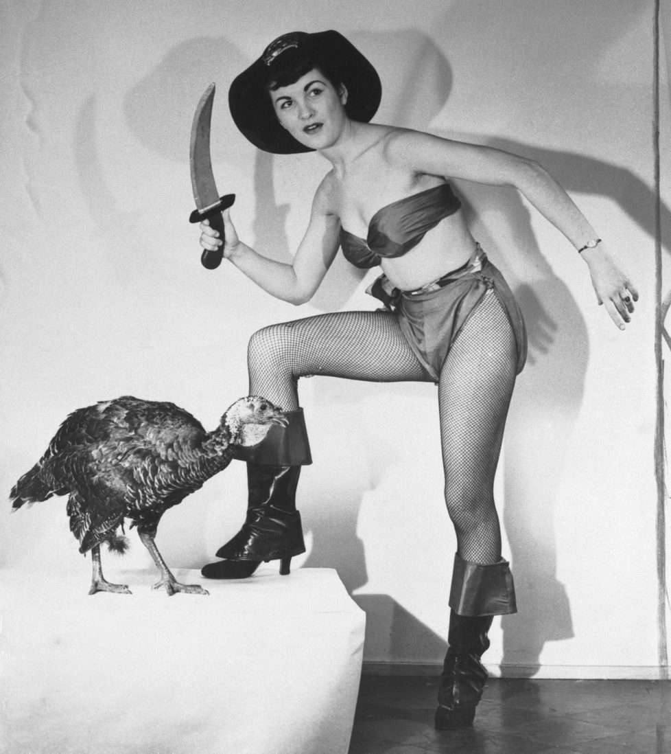 (Original Caption) The pretty buccaneer is Flo Bondi, who was Miss Ohio of 1949, but it makes little difference to the despondent turkey whether the ax is applied by a Venus or a Virago. The effect on its neck is the same. Flo is publicizing Thanksgiving and, incidentally, a motion picture called The Pirates of Capri.