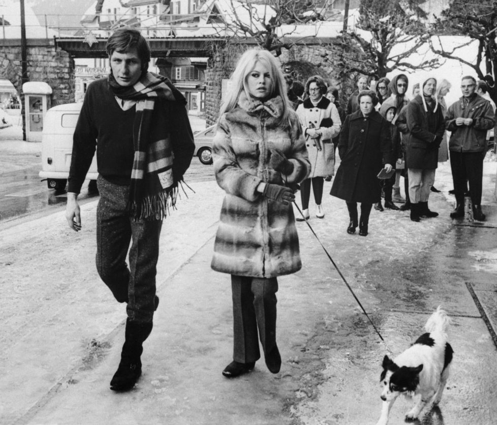 (Original Caption) Gstaad, Switzerland: French actress Brigitte Bardot and her husband, Gunther Sachs, walk their dog through the streets of Gstaad watched by curious onlookers. The couple is winter vacationing at the famous ski resort here. 1/5/1967